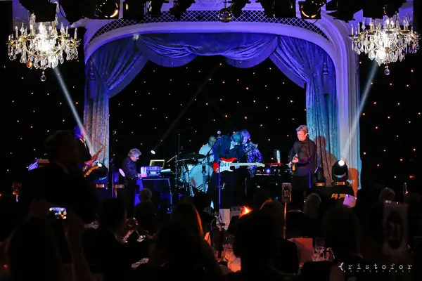 Band on stage beneath chandeliers and blue curtains at the 2014 bis Awards at The Savoy