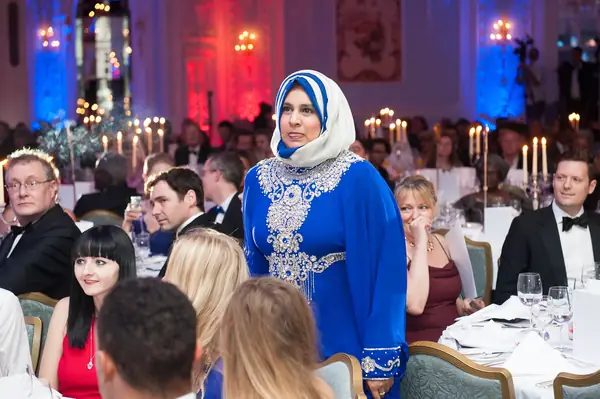 Guest in a blue embroidered dress and headscarf among the dinner tables at the 2014 bis Awards at The Savoy