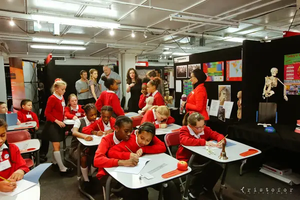 Schoolchildren in red jumpers working at desks at the British Invention Show 2014