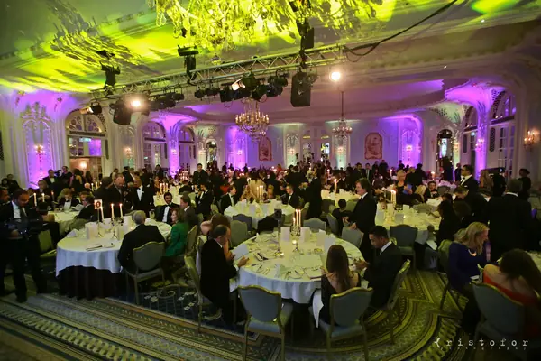 Guests at dinner under green and purple light in the ballroom at the 2014 bis Awards at The Savoy