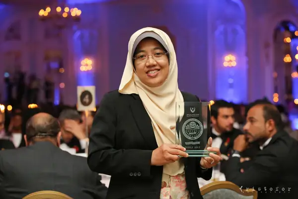 Award winner in a headscarf holding a glass award at the 2014 bis Awards at The Savoy