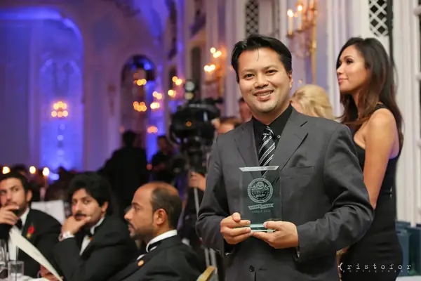 Award winner holding a glass award in the ballroom at the 2014 bis Awards at The Savoy