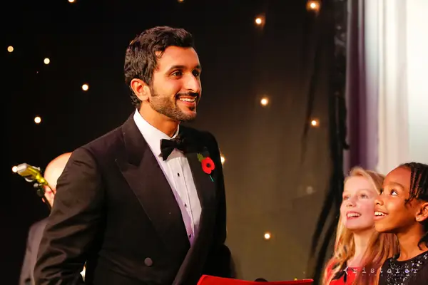 Guest in black tie wearing a poppy, smiling backstage at the 2014 bis Awards at The Savoy