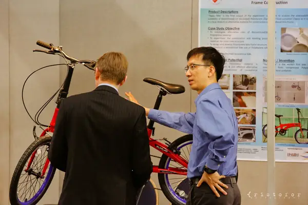 Inventor showing a red folding bicycle to a visitor at the British Invention Show 2014