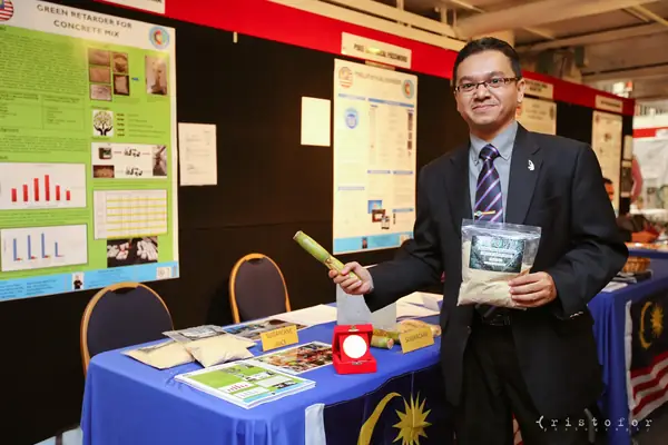 Exhibitor from Malaysia showing a sample beside his posters at the British Invention Show 2014