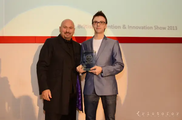 Young winner holding a glass award on stage at the British Invention Awards 2013
