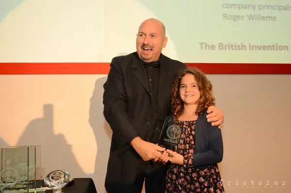 Young winner holding a glass award on stage at the British Invention Awards 2013